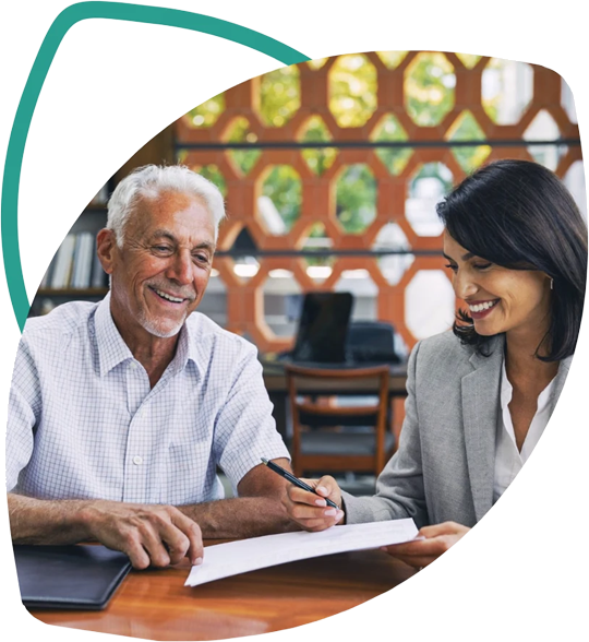 Cliente aposentado sorrindo ao assinar documentos com uma especialista da Baru Financeira