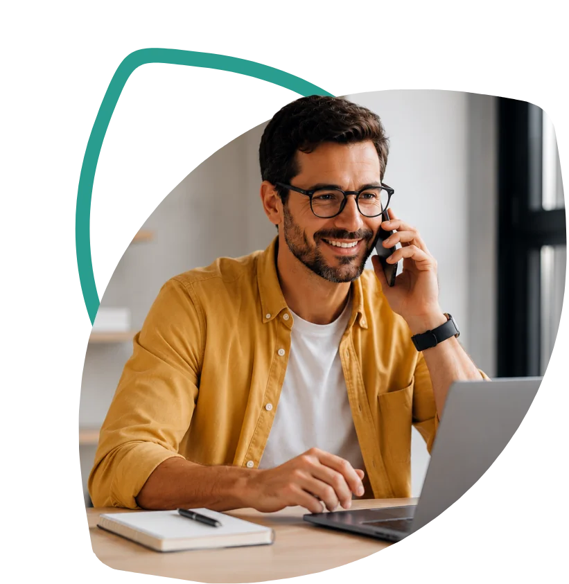 Cliente sorrindo ao telefone, diante do notebook, ao conversar sobre seu crédito