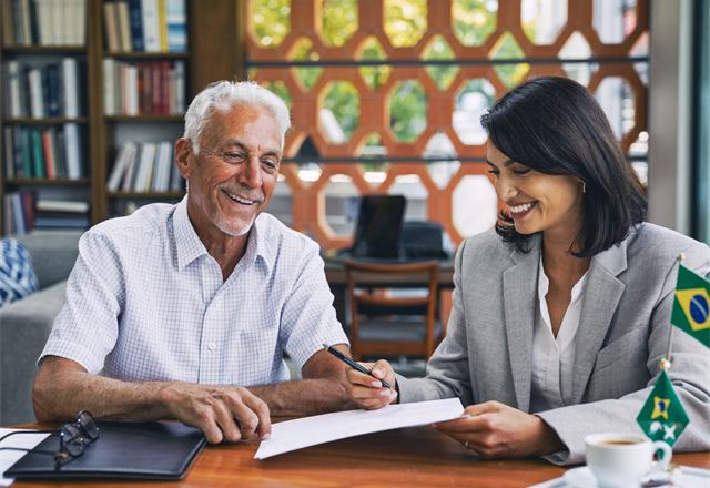 Cliente aposentado assinando documentos com uma especialista